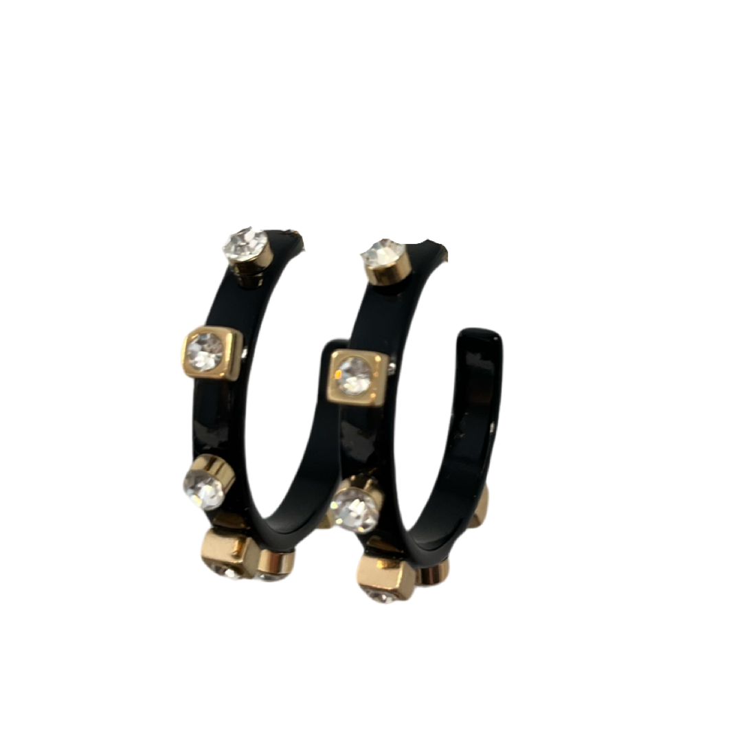 A pair of glossy black hoop earrings adorned with gold studs and clear jewels are displayed against a white background, highlighting their sleek design.