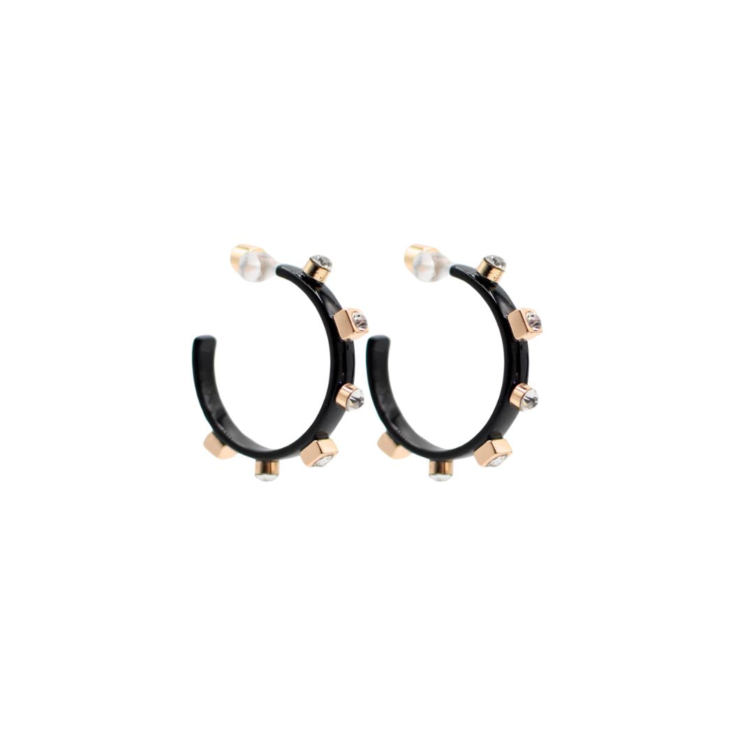 A pair of metallic black hoop earrings with gold studs and clear jewel accents, set against a white background to highlight their reflective surfaces.