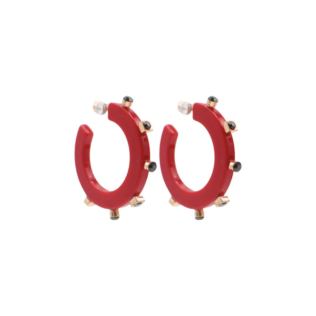 Small bright red open hoop earrings with gold-tone accents and black crystal studs along the edge, featuring a sleek design and clear post backings.