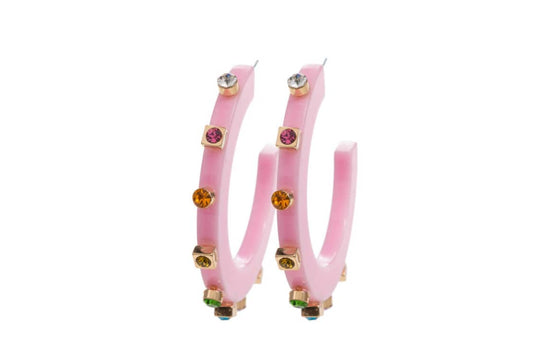 Two pink acrylic hoop earrings standing upright against a white background, adorned with colorful gemstones in gold settings with vibrant reflections.