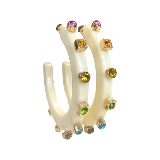 A pair of ivory-colored hoop earrings embellished with vibrant gemstones, featuring accents in pink, yellow, orange, green, and blue hues.