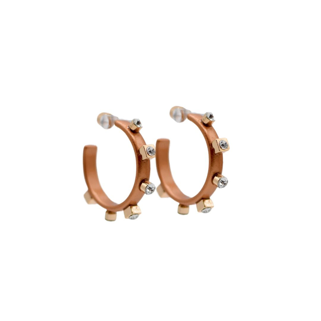 A pair of orange metal hoops with six evenly spaced gold studs and small crystal jewels adorning each stud, set against a white background.