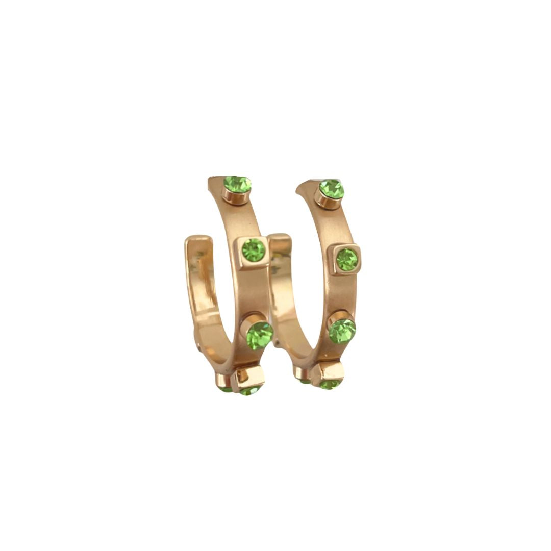 A pair of gold brushed metal hoop earrings with gold studs and green jewel accents, set against a white background to highlight their reflective surfaces.