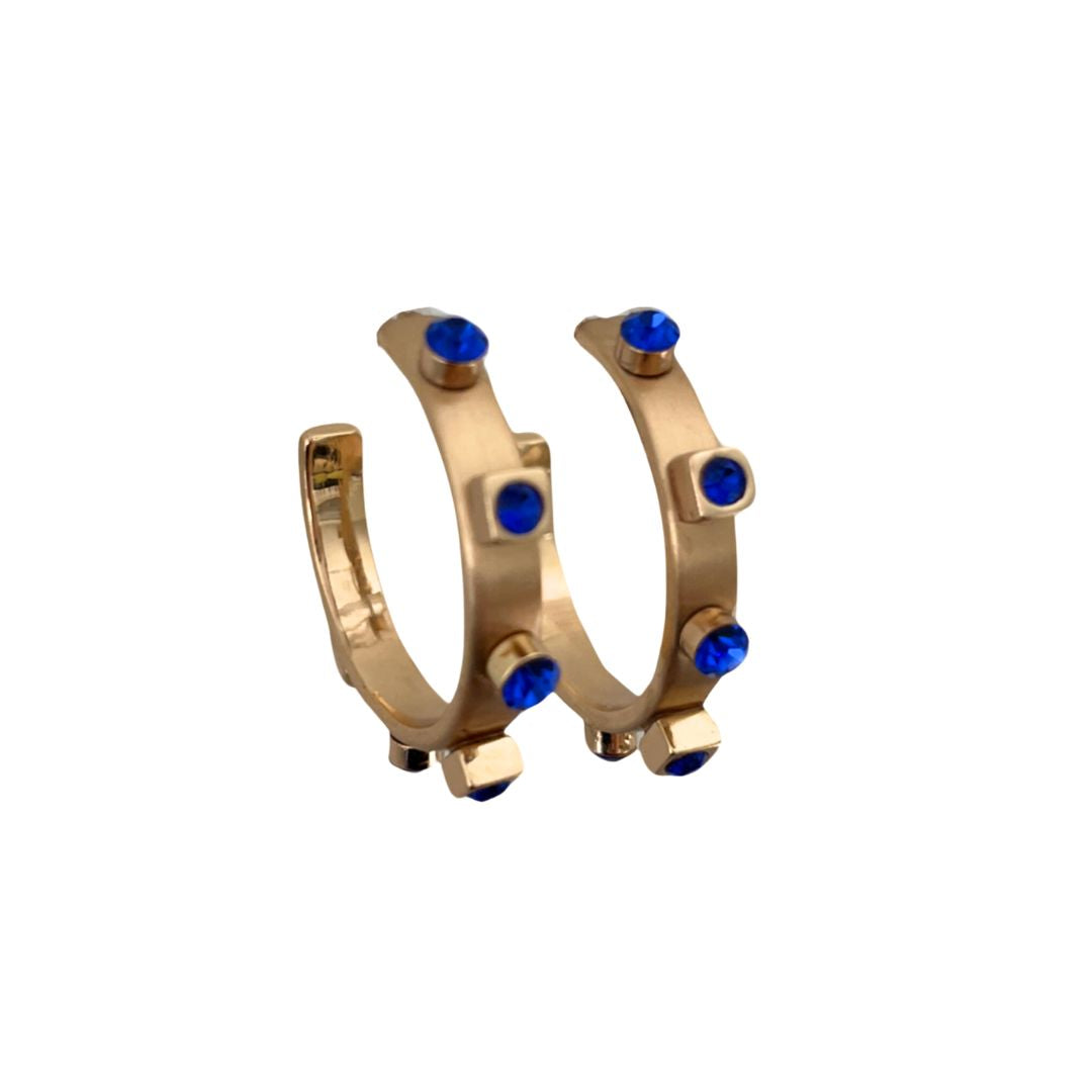 A pair of 14k brushed gold metal hoop earrings with six gold studs and sapphire jewel accents, set against a white background.