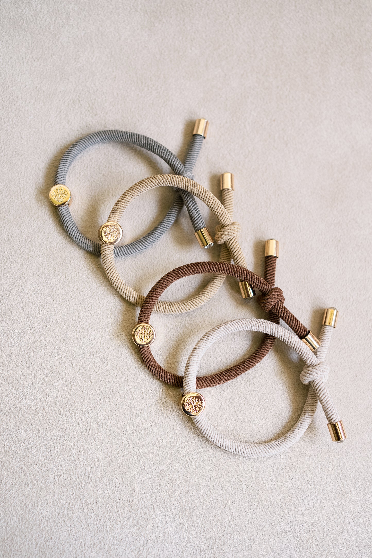 Neutral-tone thick elastic hair ties with gold end caps, featuring a stylish and durable design in shades of grey, beige, brown, and cream.