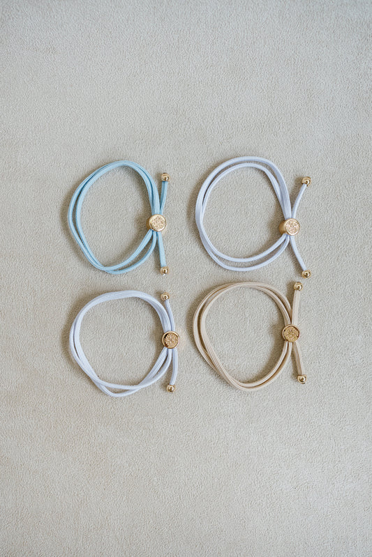 The Bride To Be Hair Tie Set comes in a set of 4 with shades of white, tan, and light blue.