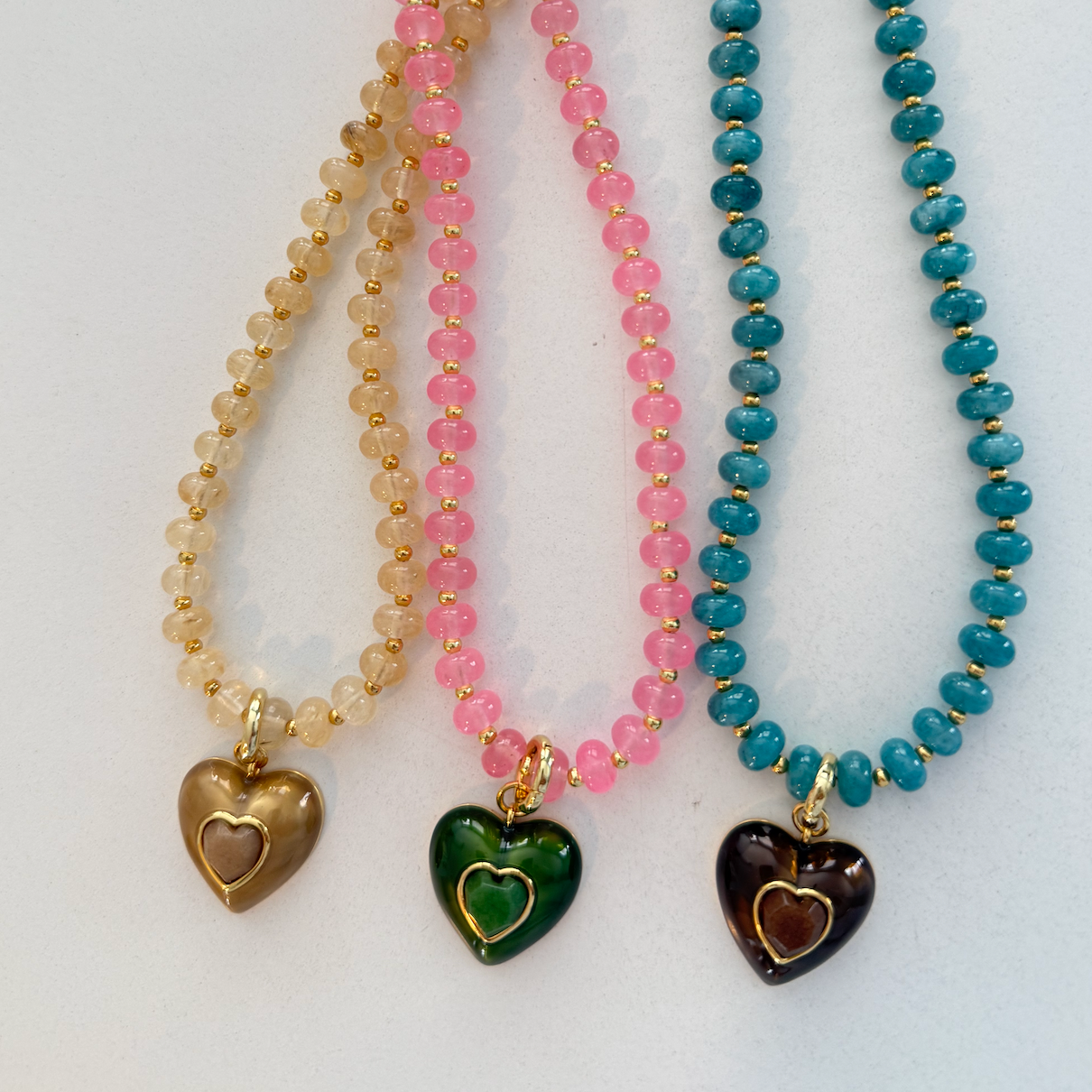 Three beaded necklaces with heart-shaped charms on a white background