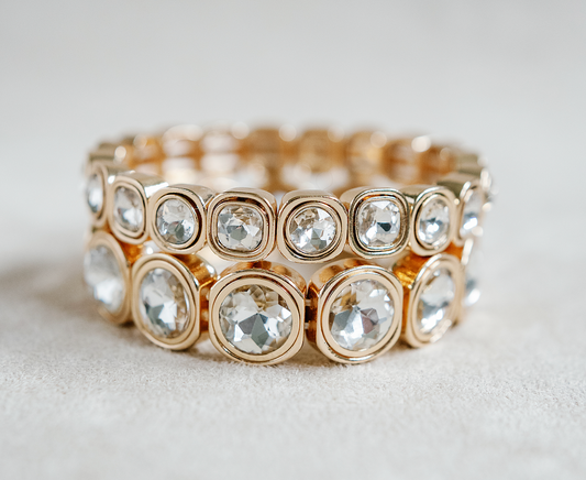 A gold-toned bracelet with circular crystal accents, each housed in rounded square frames, arranged symmetrically around the band for a reflective effect. Gold Bracelet stack