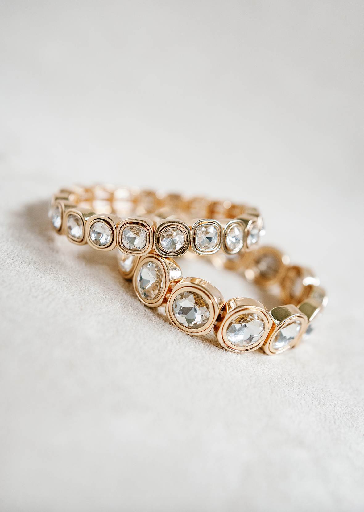 A stretch bracelet with gold-tone square settings, each holding a sparkling round crystal, offering a sleek and luxurious design perfect for layering. Petite and Round Braclets