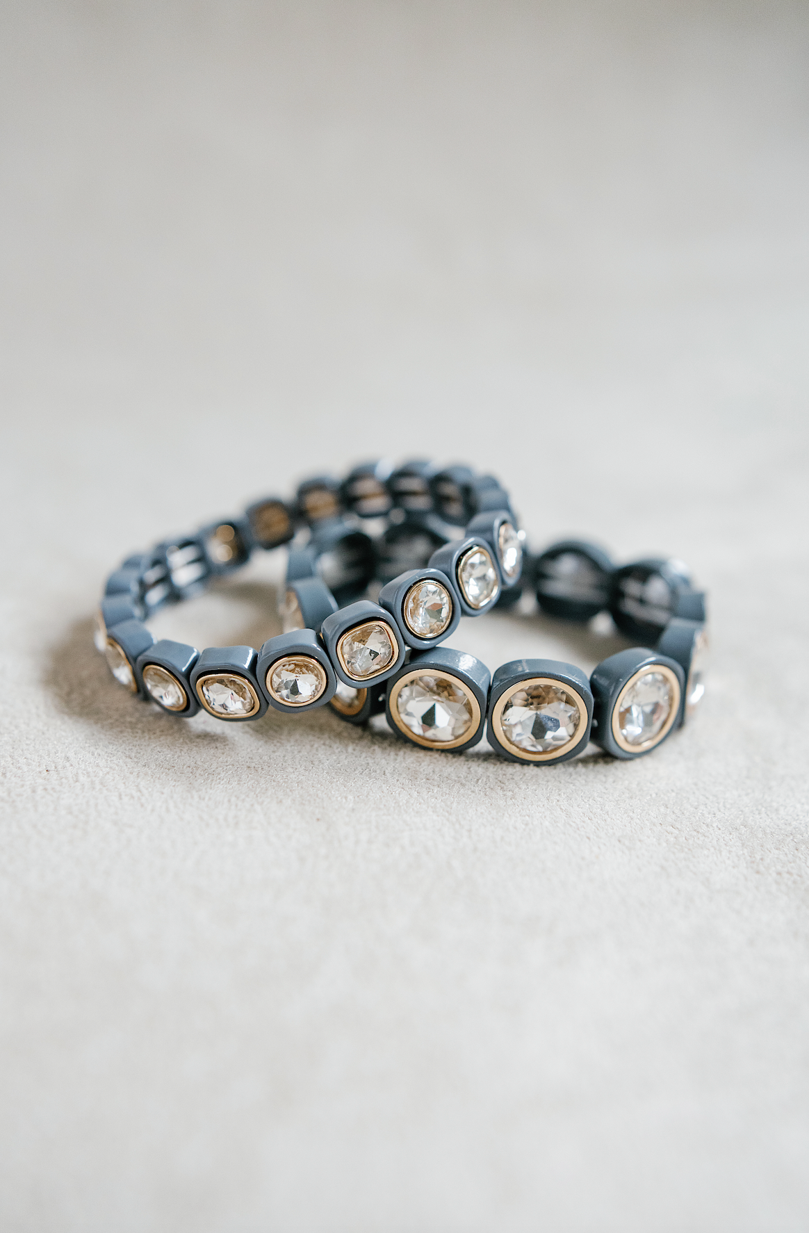 A light gray bracelet featuring large, faceted gemstones framed in gold settings, arranged in a circular, stretchy design ideal for a snug fit. Petite and Round bracelet stack.