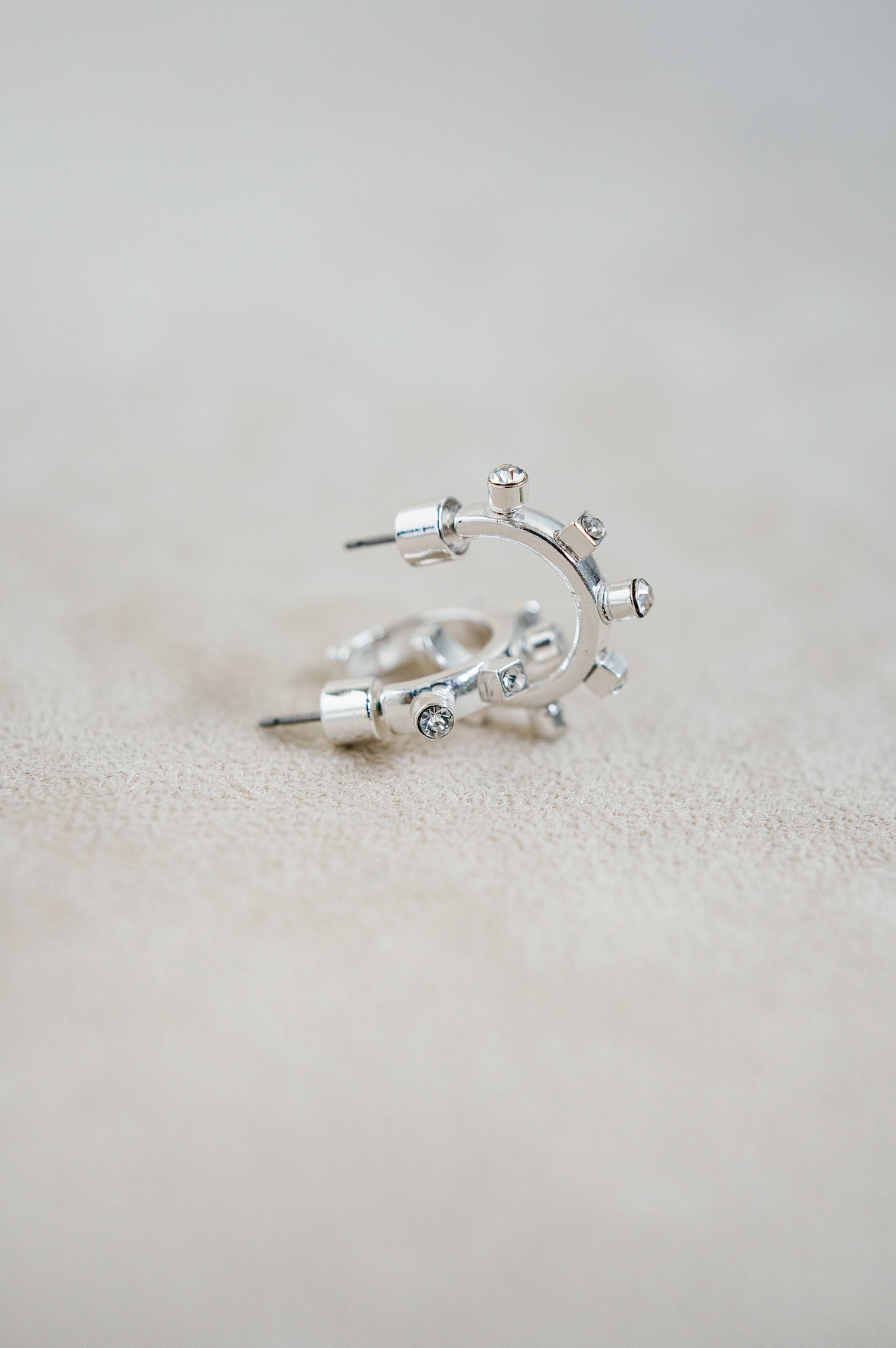 A close-up view of two silver hoop earrings with unique bolt-shaped jewel details arranged around the outer edge.