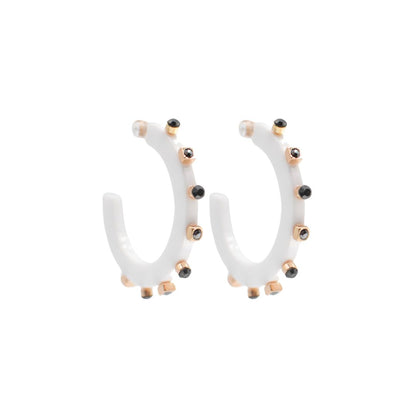 Large white open hoop earrings with gold-tone accents and black crystal studs along the edge, featuring a modern design and clear post backings.