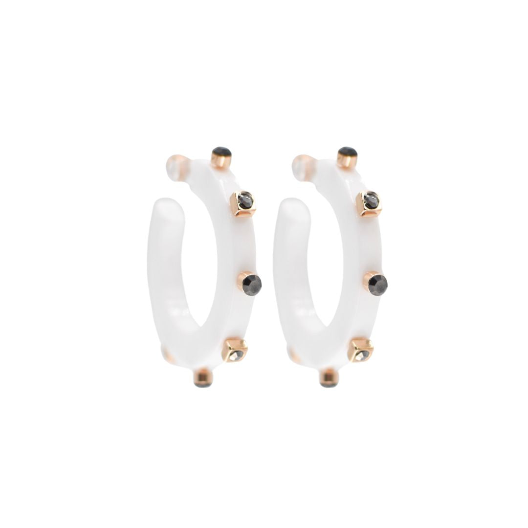 Small white open hoop earrings with gold-tone accents and black crystal studs along the edge, featuring a modern design and clear post backings.