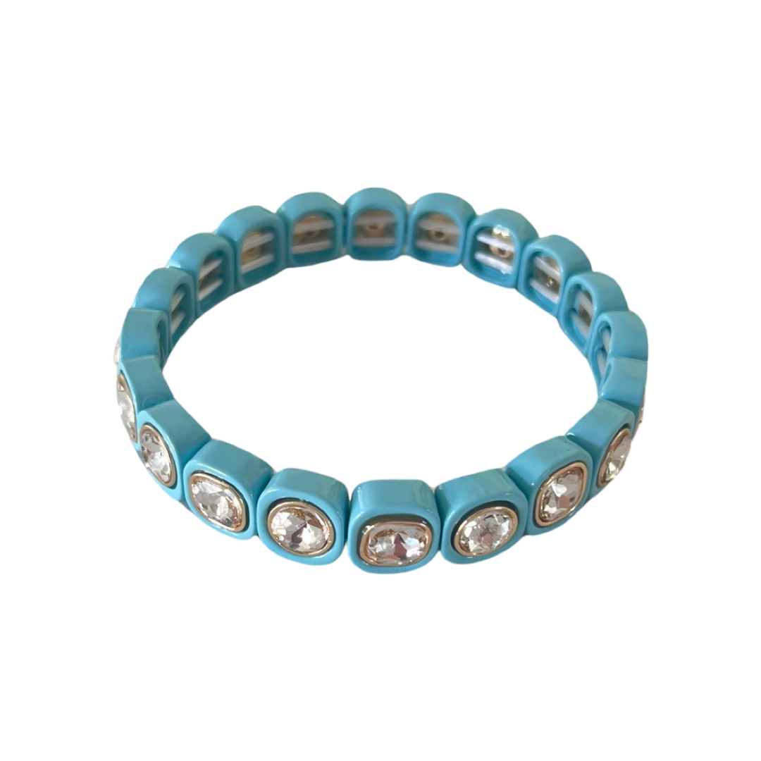 A circular bracelet in glossy light blue, featuring square-shaped links with embedded clear gemstones, arranged seamlessly around its stretchable band.