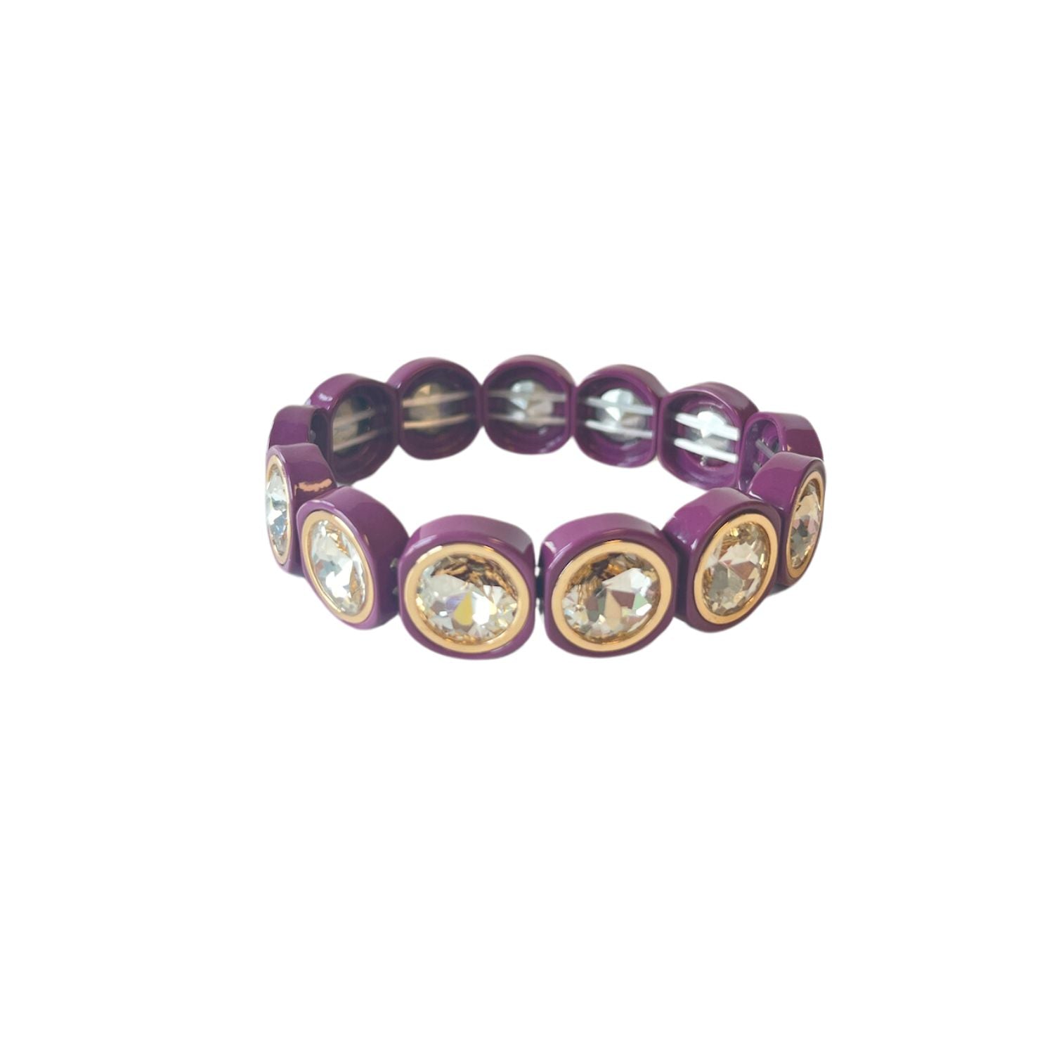 A purple bracelet features large, circular crystal stones encased in rounded gold frames, evenly spaced with elastic threading against a white background.