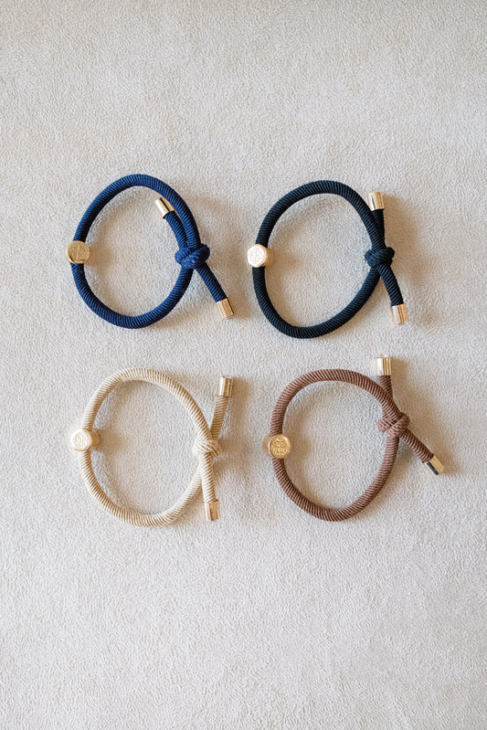 Set of four thick elastic hair ties in dark neutral tones, featuring gold metal accents and a knotted design, perfect for durable and stylish hair styling.