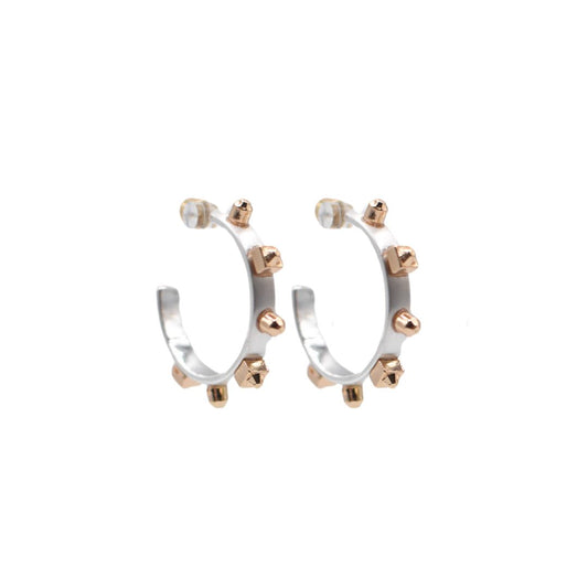 A pair of silver hoop earrings with matte gold studs, set against a white background to highlight their reflective surfaces.