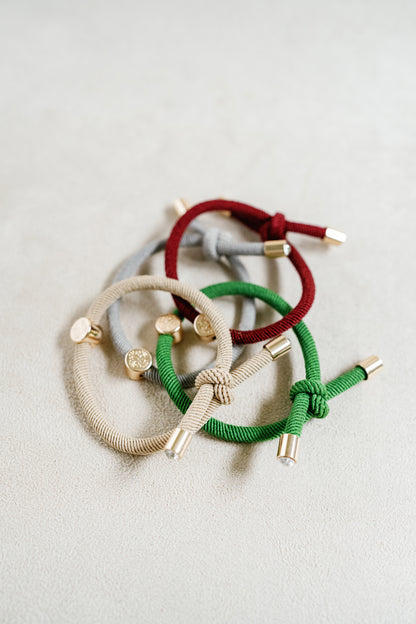 The Christmas Hair Tie Set Comes in a set of 4 in shades of cranberry, light grey, christmas green , and tan 