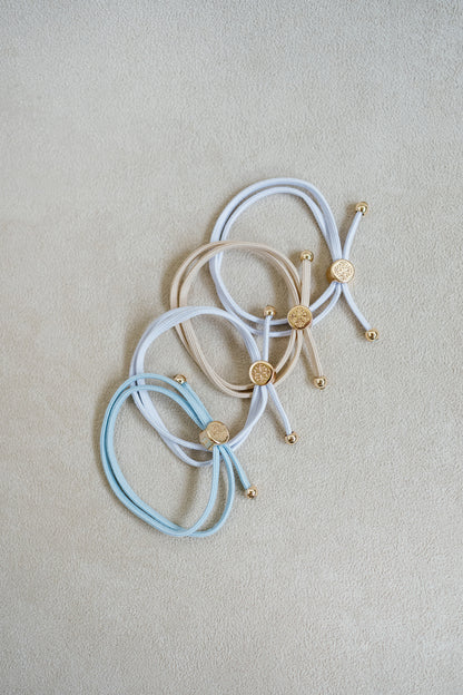 The Bride To Be Hair Tie Set comes in a set of 4 with shades of white, tan, and light blue.