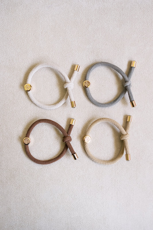 Set of four thick elastic hair ties in neutral tones, featuring gold metal accents and a knotted design, perfect for durable and stylish hair styling.