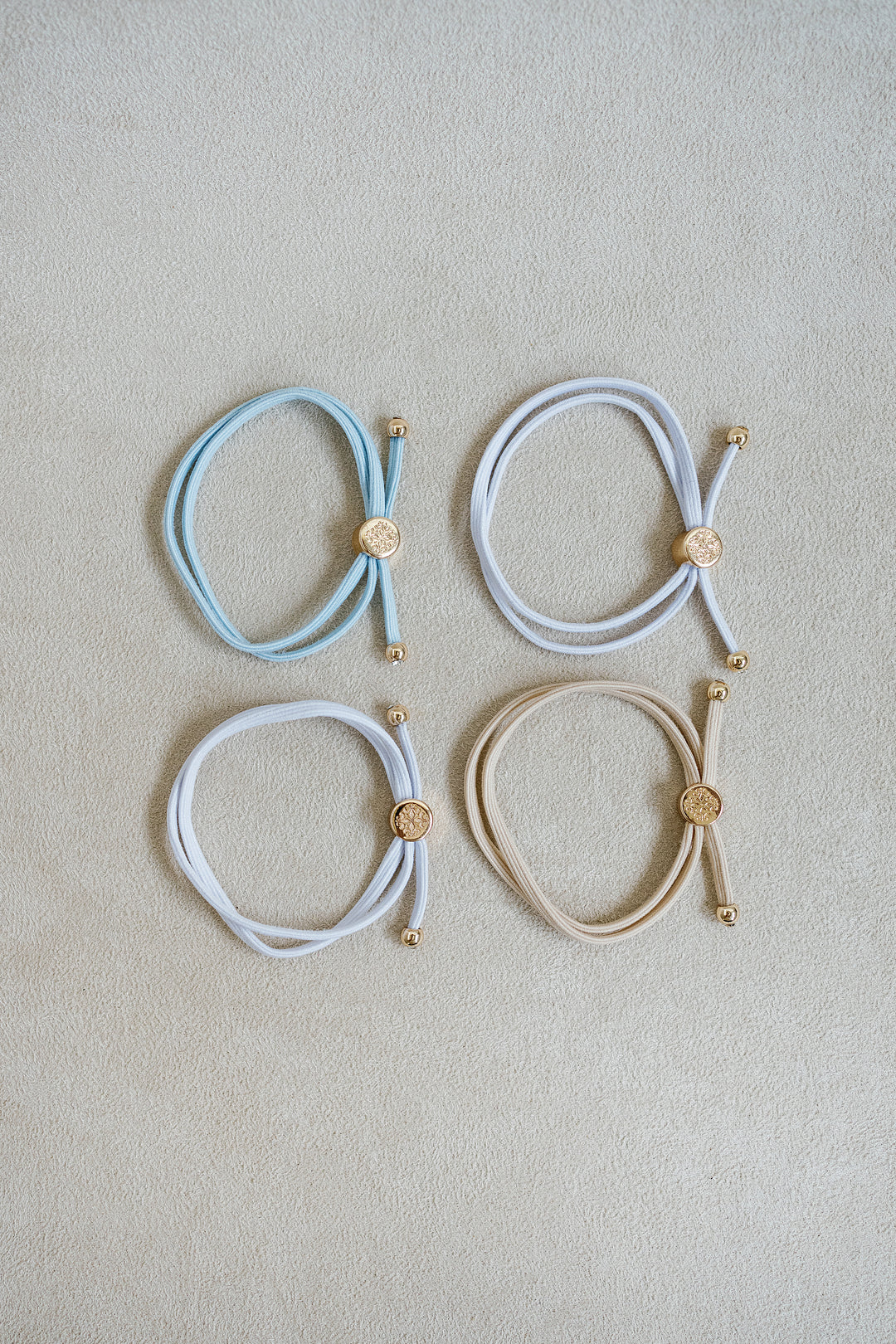 The Bride To Be Hair Tie Set comes in a set of 4 with shades of white, tan, and light blue.