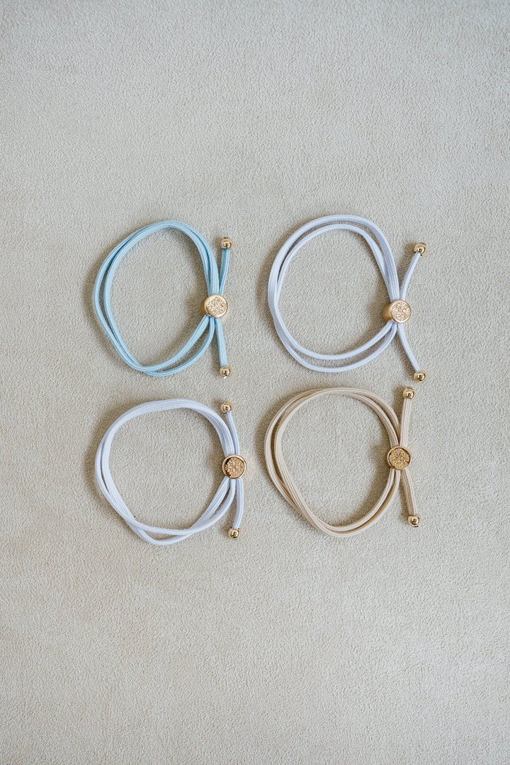 The Bride To Be Hair Tie Set comes in a set of 4 with shades of white, tan, and light blue.