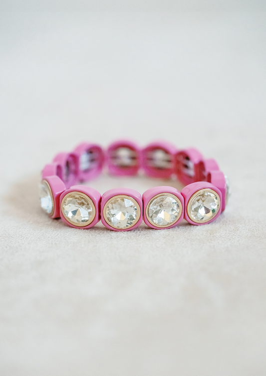 Enamel petite stretch bracelet in raspberry pink. Round crystal jewels with gold detail. One size fits all.