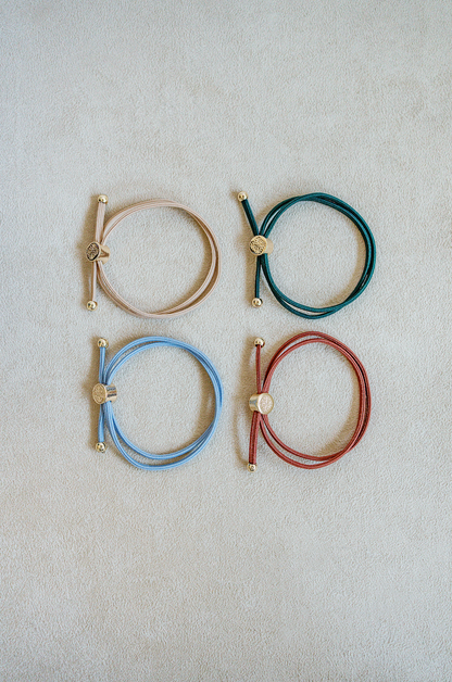 Sold as a set of 4, Skinny Hair Tie Set are double wrapped, minimal, sleek bracelets with round gold end caps and signature gold detail in Anqtique.