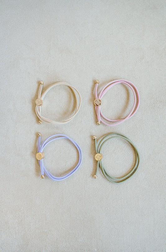 Sold as a set of 4, Skinny Hair Tie Set are double wrapped, minimal, sleek bracelets with round gold end caps and signature gold detail in Ballet Slipper