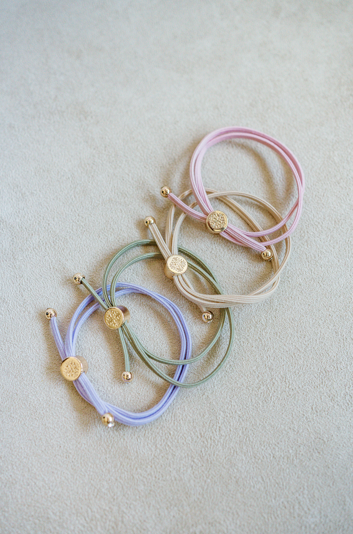 Sleek Skinny Hair Tie Bracelet sold as a set of four in pink, khaki, light green, and violet.