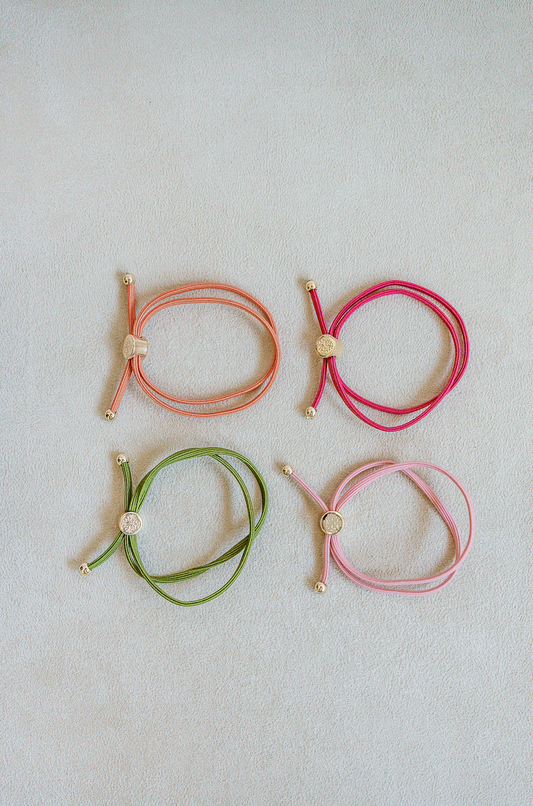 Sold as a set of 4, Skinny Hair Tie Set are double wrapped, minimal, sleek bracelets with round gold end caps and signature gold detail in Watermelon.