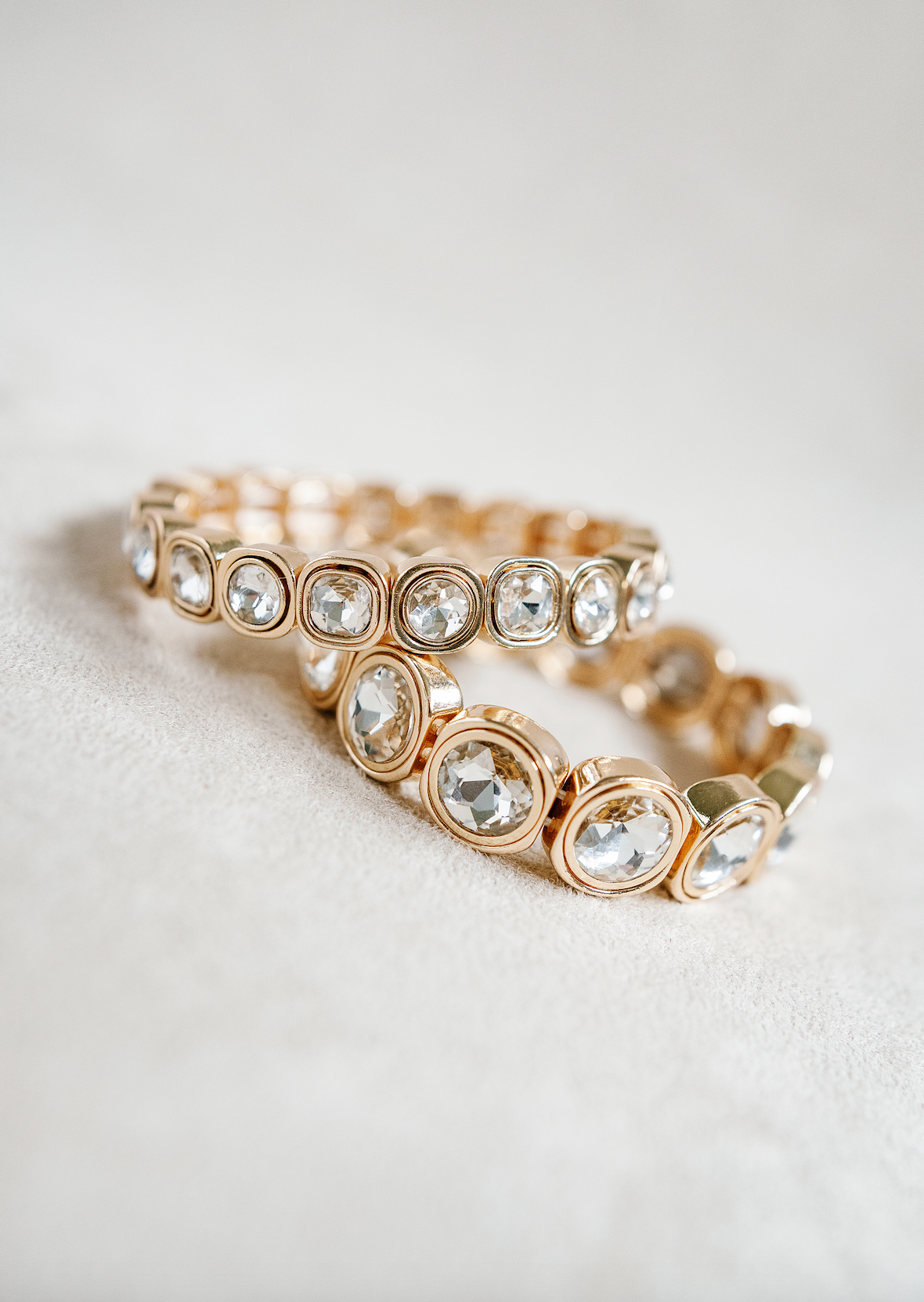 A stretch bracelet with gold-tone square settings, each holding a sparkling round crystal, offering a sleek and luxurious design perfect for layering. Petite and Round Braclets 