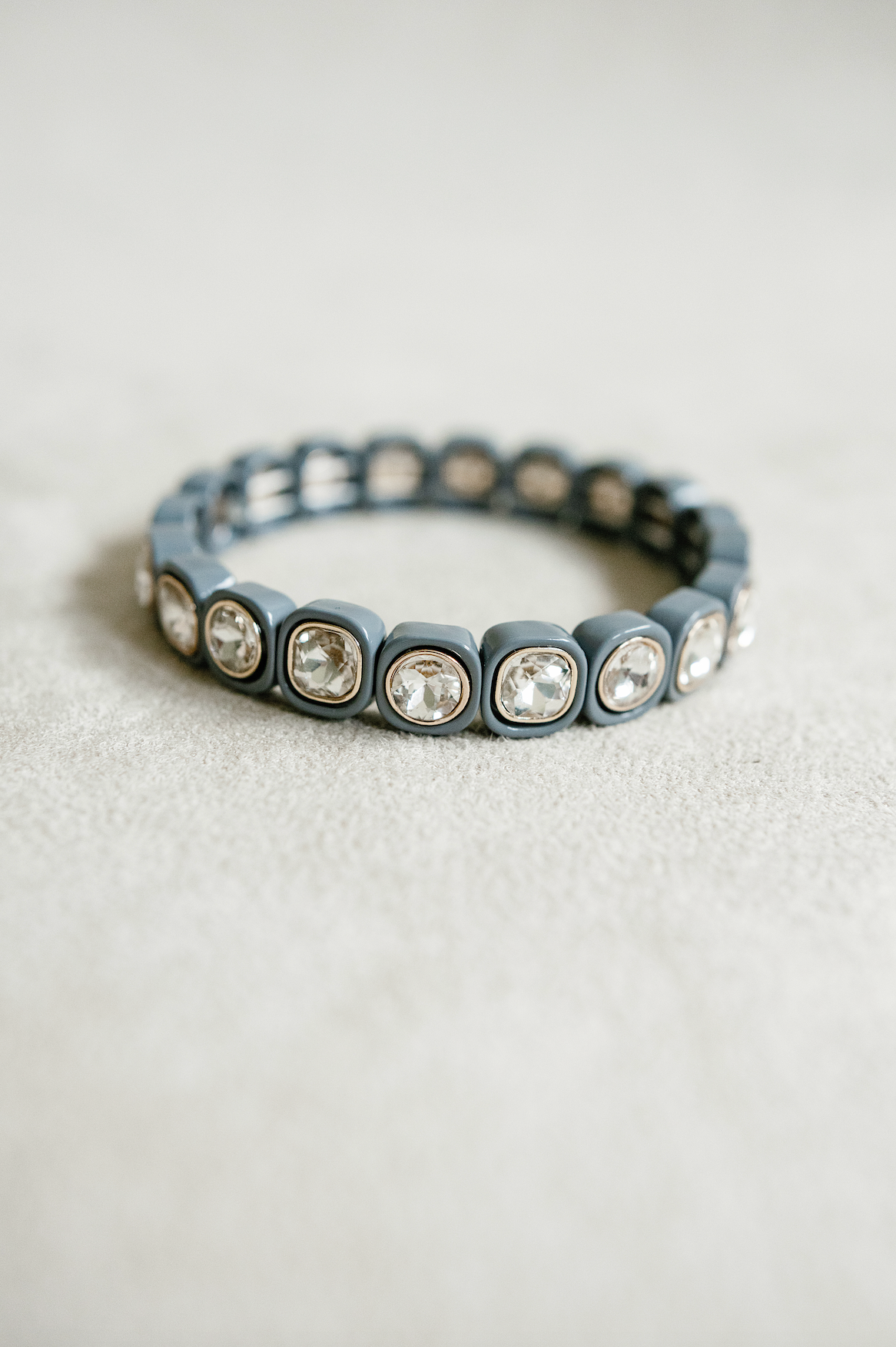 A chic stretch bracelet with dark gray square-shaped links, each adorned with faceted clear crystals framed in gold, offering an elegant, modern touch.