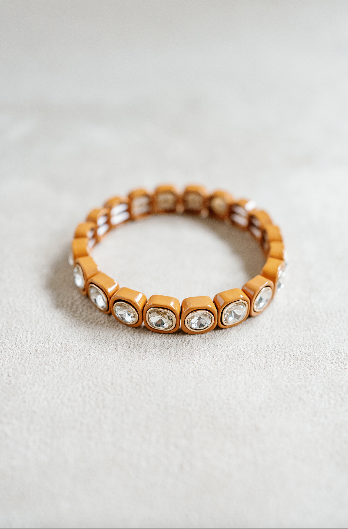 A caramel-toned stretch bracelet with cushion-cut crystal accents embedded in square-shaped settings, creating a sleek, glossy statement accessory.