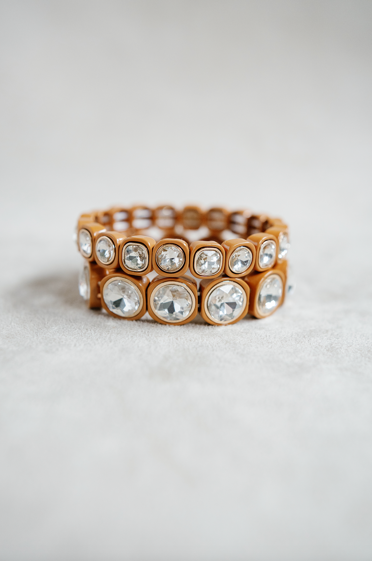 A caramel-toned stretch bracelet with cushion-cut crystal accents embedded in square-shaped settings, creating a sleek, glossy statement accessory.