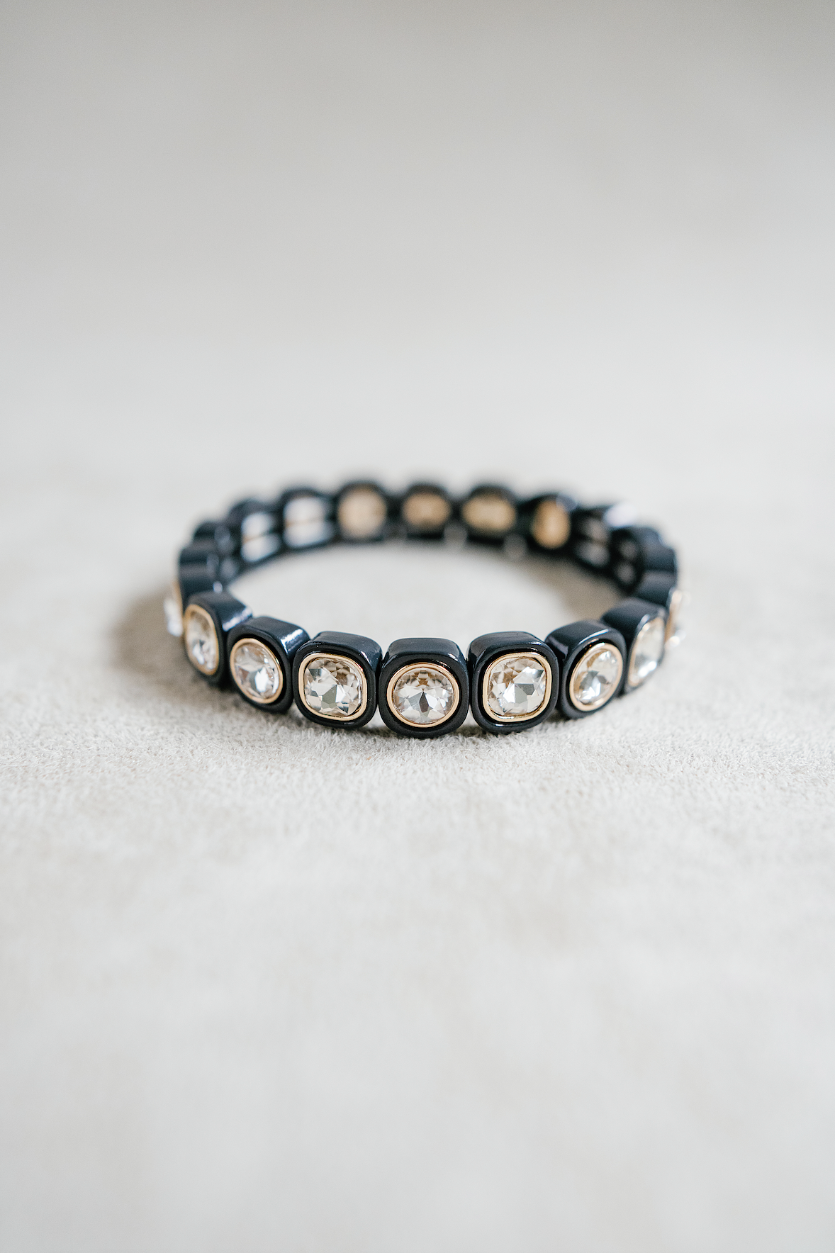 A sleek black bracelet featuring cushion-cut crystal accents encased in glossy, square settings, creating a bold yet elegant statement piece.