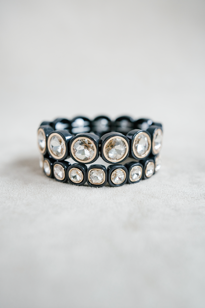 A sleek black bracelet featuring cushion-cut crystal accents encased in glossy, square settings, creating a bold yet elegant statement piece. Round and Petite Bracelet Stack