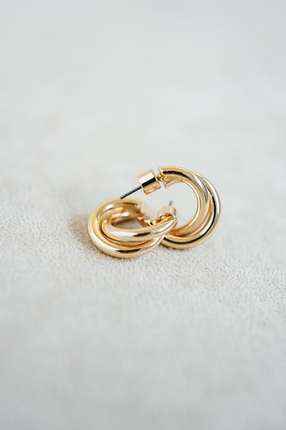 gold huggie hoop earring with twisting detail.