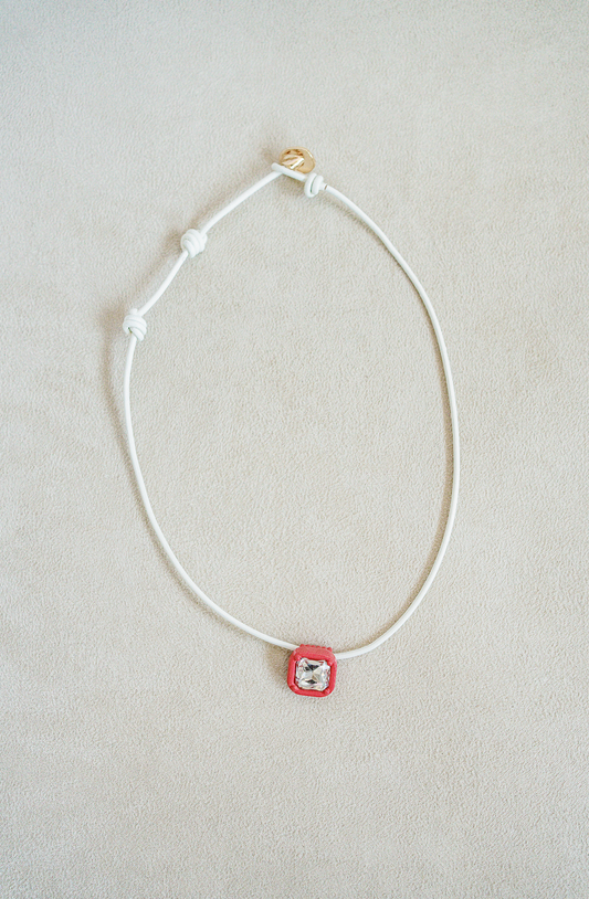 Leather necklace with signature square acrylic jewel center in an enamel setting. Adjustable sizing with knotted loop.