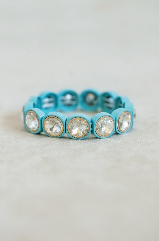 Round acrylic jewel stretch bracelet with gold detailed edging for a complete finish. Adjusts to fit wrist with elastic band in blue hawaiian.