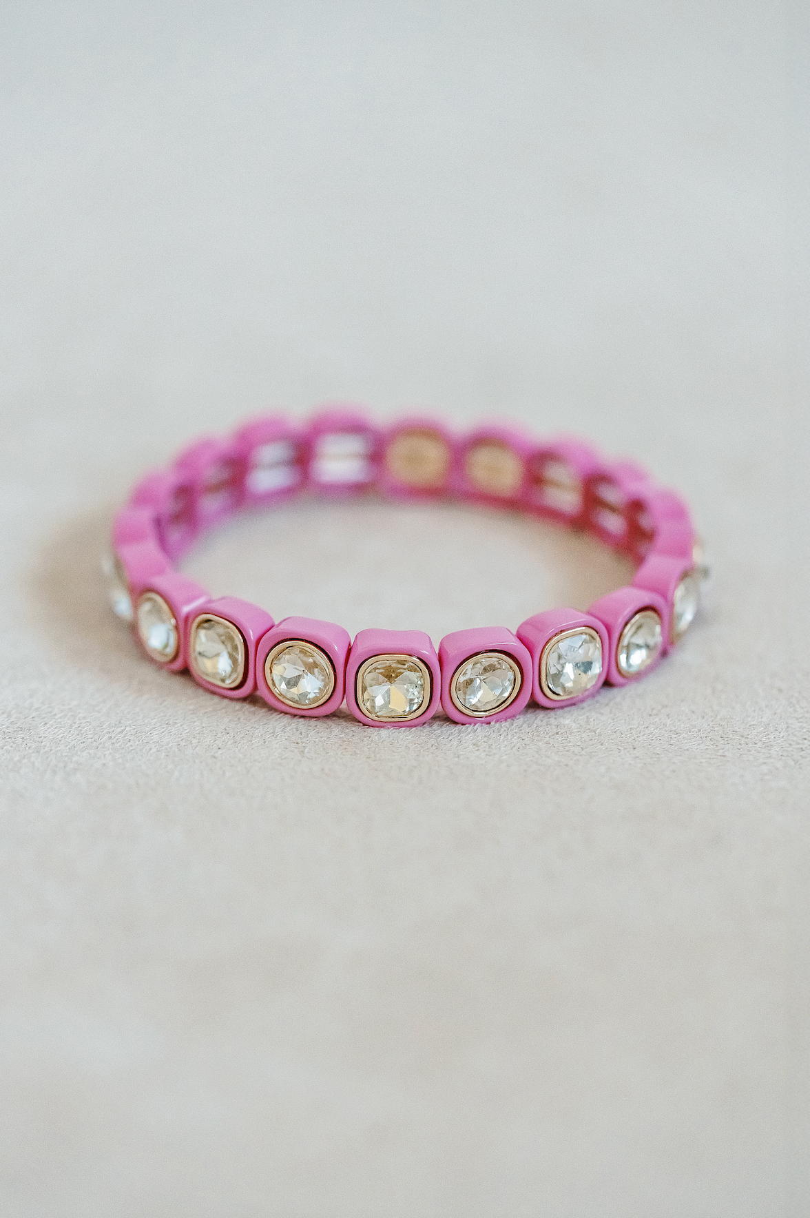 Petite, alternating enamel stretch bracelet. Adjusts to fit wrist with elastic band. Gold detail finish in raspberry pink.