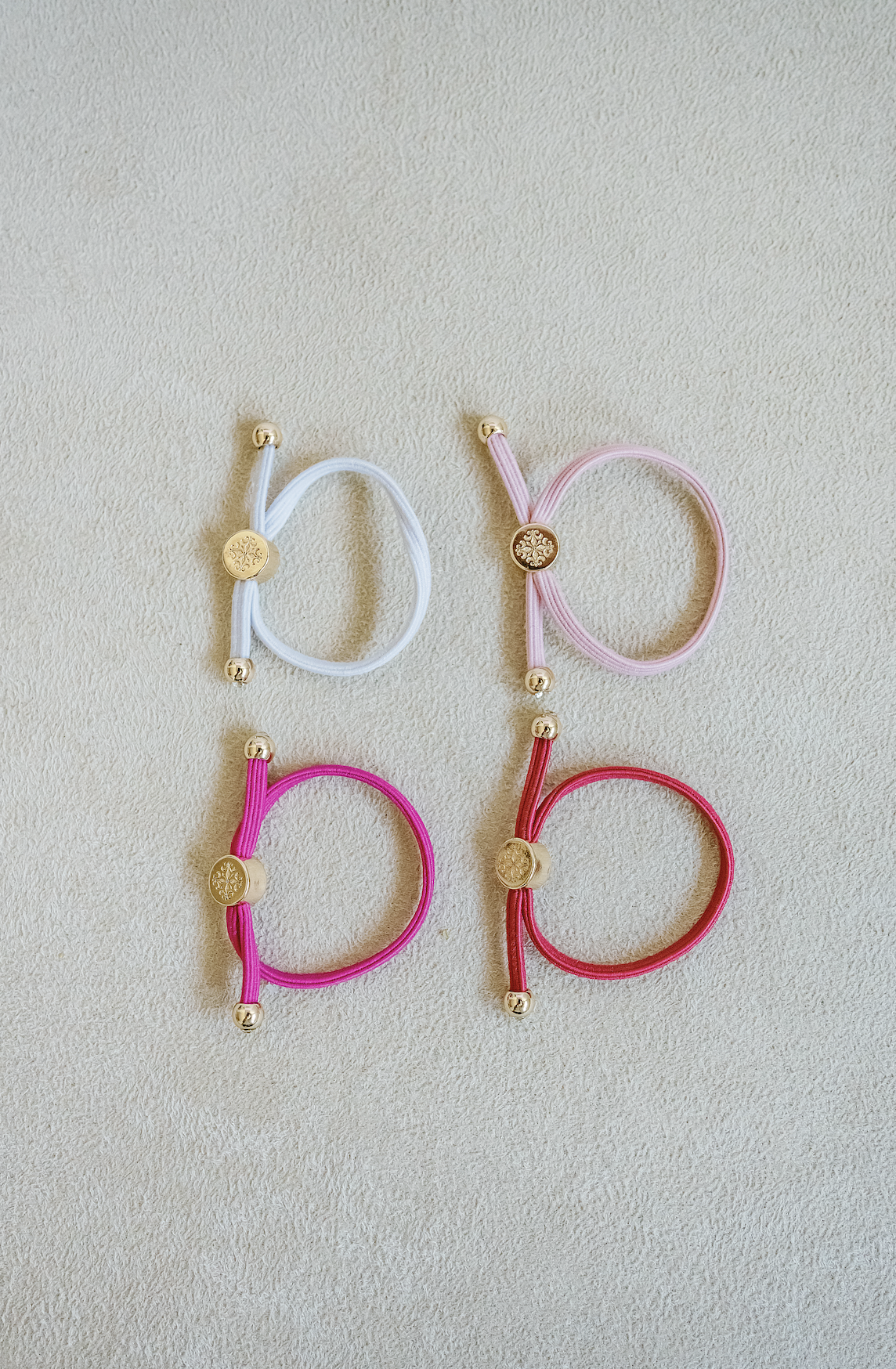 Sold as a set of 4, Children's Size single strand skinny Hair Tie Set are bracelets with round gold end caps and signature gold detail in pink.