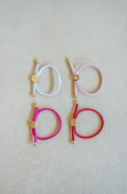 Sold as a set of 4, Children's Size single strand skinny Hair Tie Set are bracelets with round gold end caps and signature gold detail in pink.