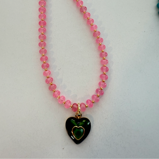 Necklace with pink beads and a green heart pendant on a white background