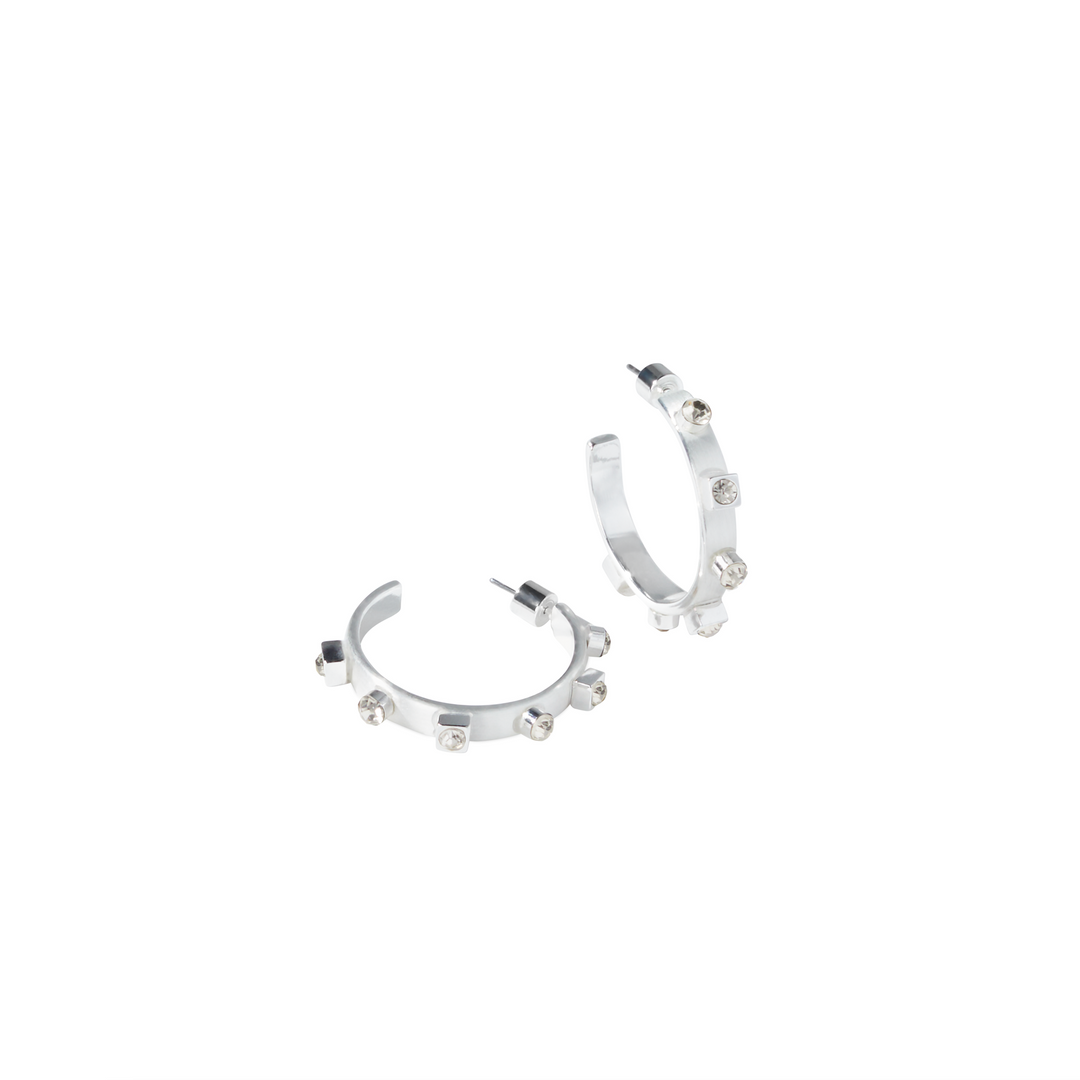 Two silver hoop earrings with crystal gemstones  are positioned on a white background, with one earring lying flat and the other standing upright.