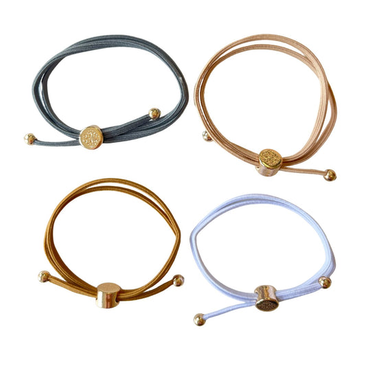 Four stylish elastic hair ties with adjustable gold metal clasps in shades of grey, beige, gold, and white, designed for a secure and elegant look.