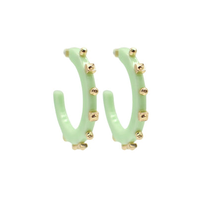 Large pale green open hoop earrings with gold-tone square and round studs along the edge, featuring a sleek, lightweight design and clear post backings.