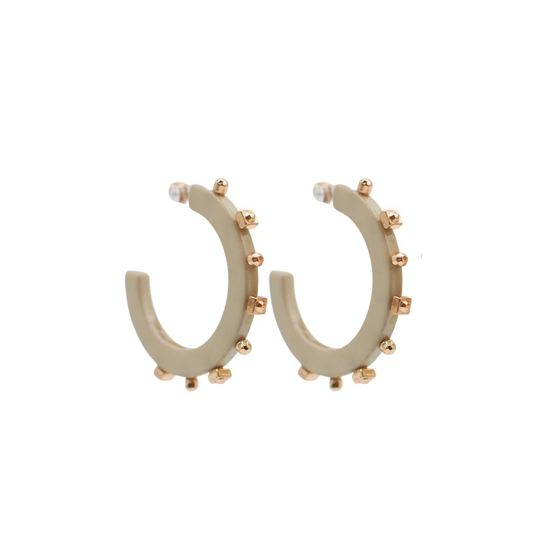 Large matte beige acrylic hoop earrings featuring gold-tone studs along the outer edge, with a sleek, open design and clear backings.